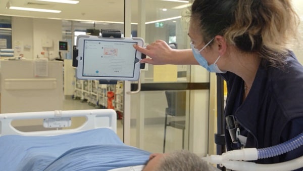 A nurse touches the device screen to start the virtual visit