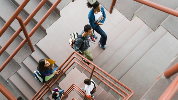 Diverse group of students with backpacks and books walking up stairway