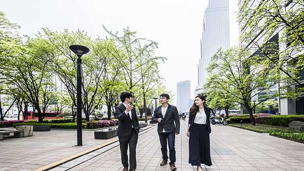 Três empresários conversando e andando na calçada